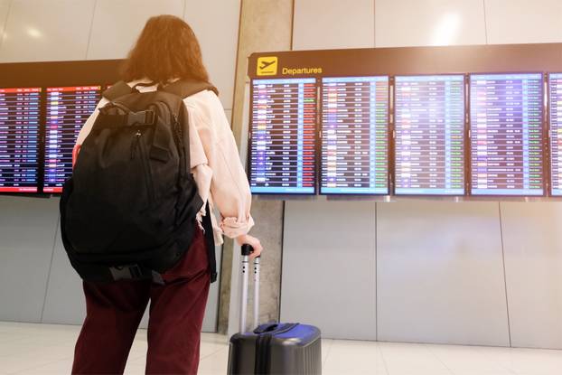 A traveler woman check her flight in Airport monitor 