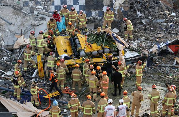 South Korean firefighters search for passengers from a bus trapped by the debris of a collapsed building in Gwangju