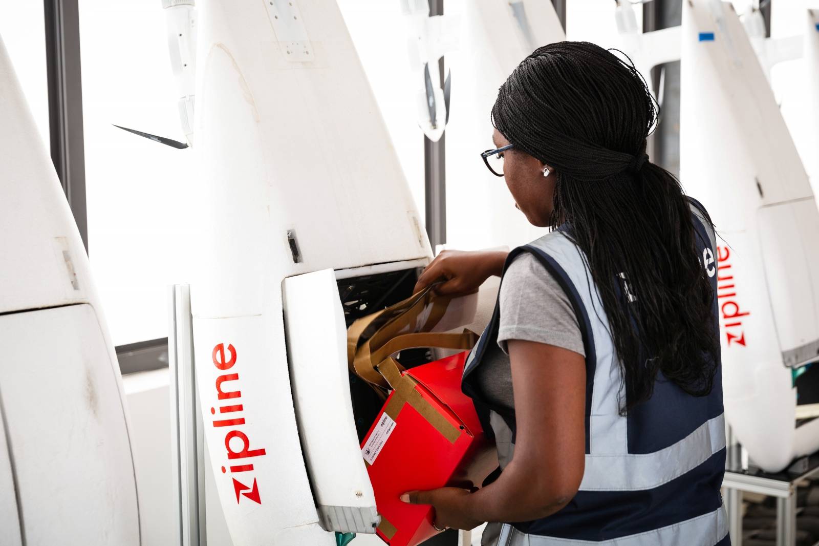 A woman packs a box of vaccines to be delivered by a Zipline drone, in Ghana