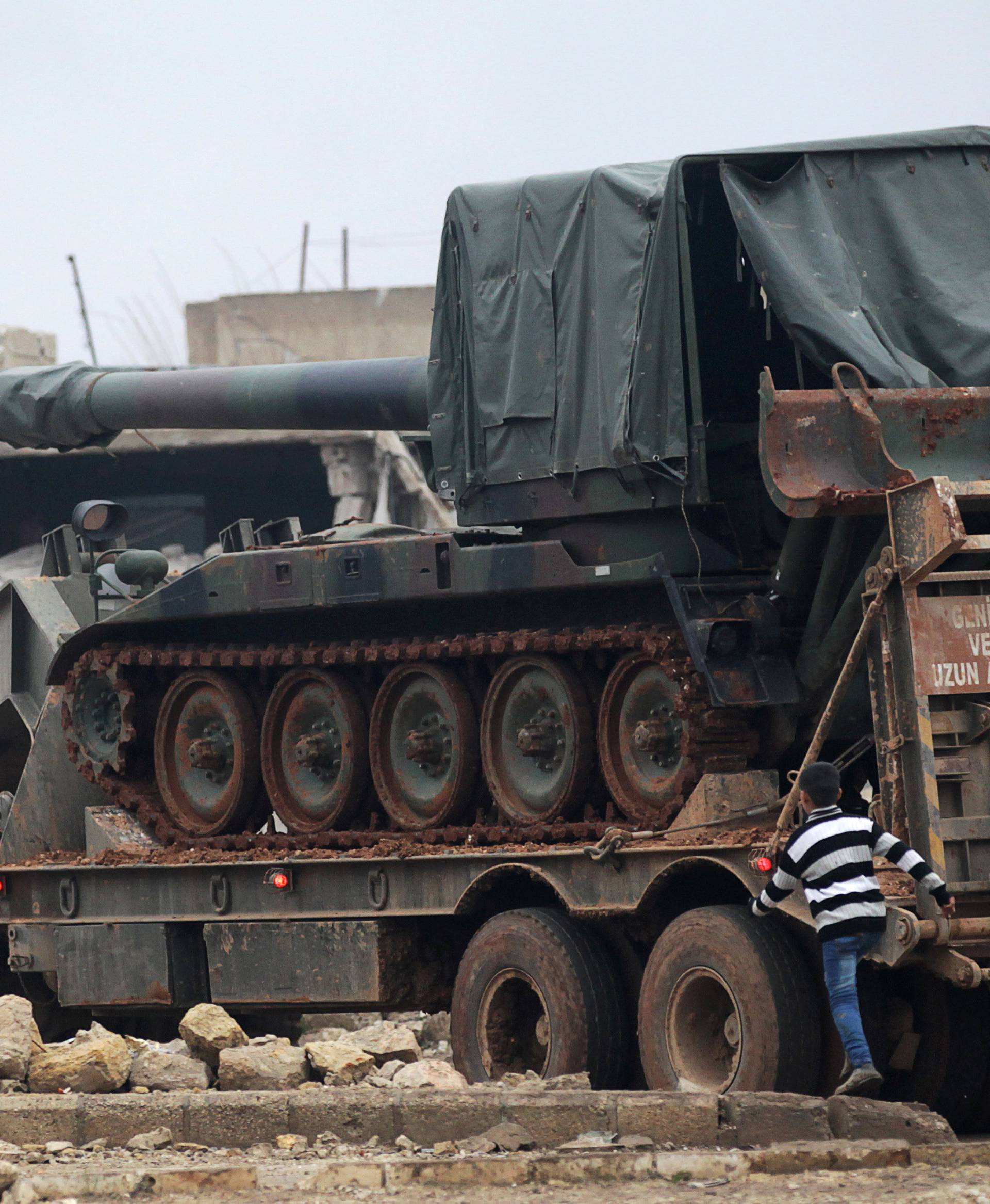 A boy walks past a Turkish tank mounted on a transporter in the northern Syrian rebel-held town of al-Rai