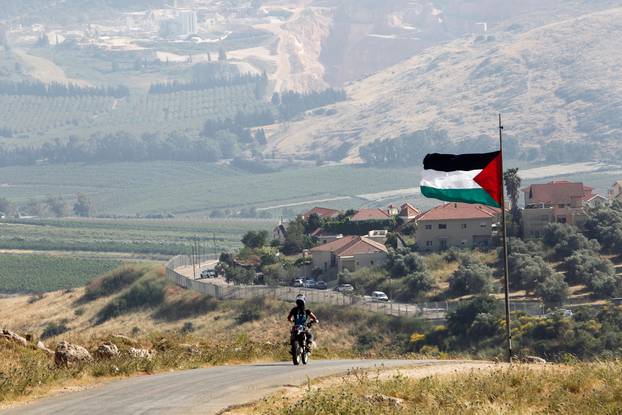 A man rides on a motorbike near a Palestinian flag in the southern Lebanese village of Khiam