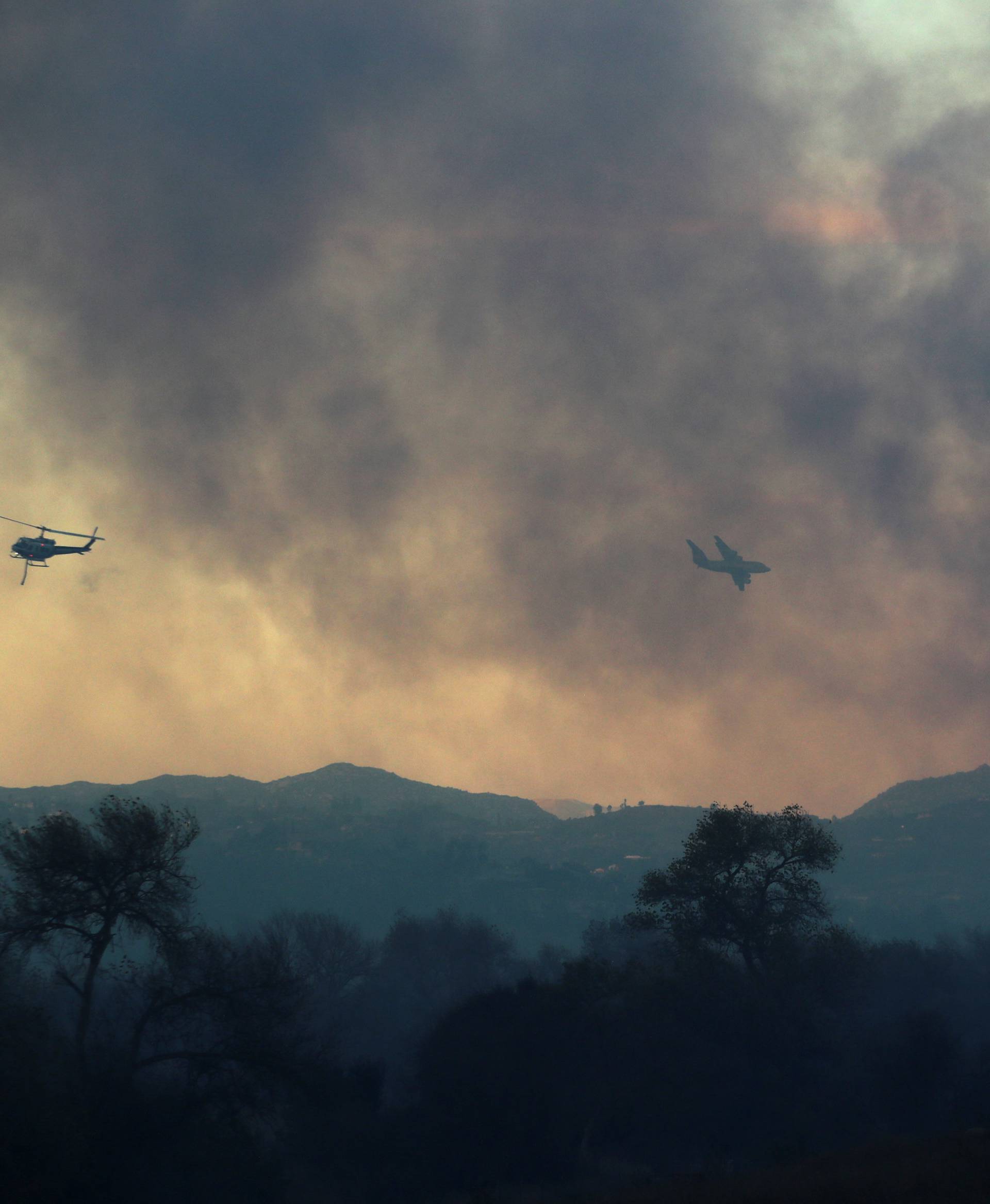 Fire fighting helicopters and water bomber douse the Lilac Fire as it burns through  Bonsall, California,