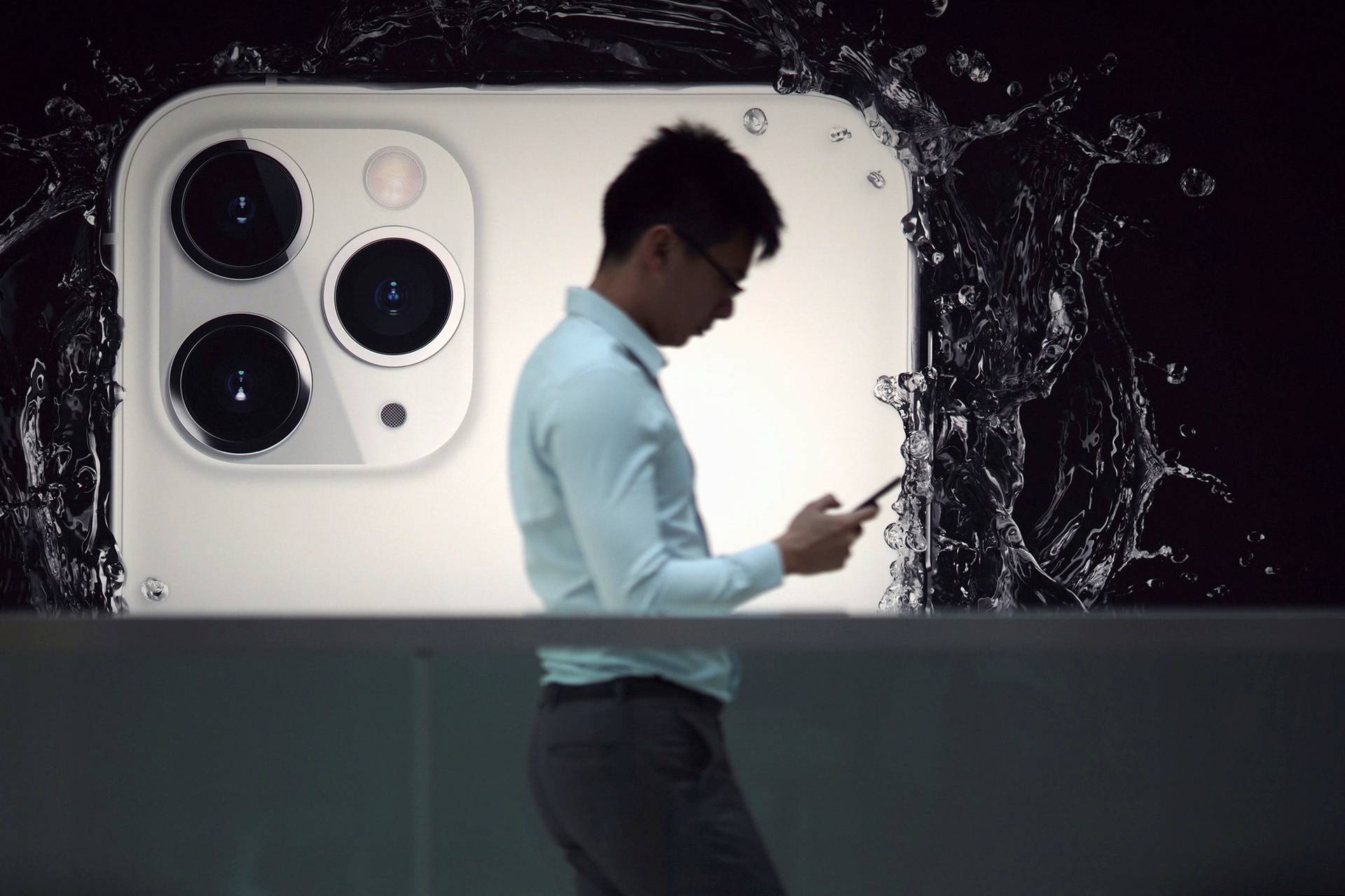 FILE PHOTO: A man walks next to an advertisement for Apple's new iPhone 11 Pro at the Apple Store in IFC, Central district, Hong Kong, China