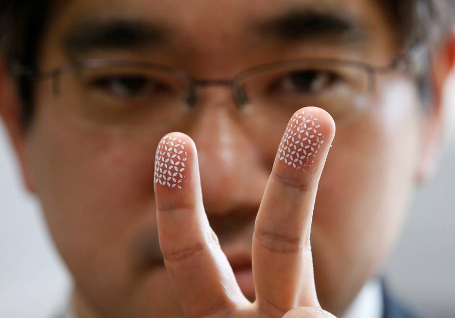 Echizen, a professor at Japan's National Institute of Informatics, poses to a photographer as he gestures with his fingers covered with a home-made biometric jammer during a demonstration of his experiment for Reuters in Tokyo