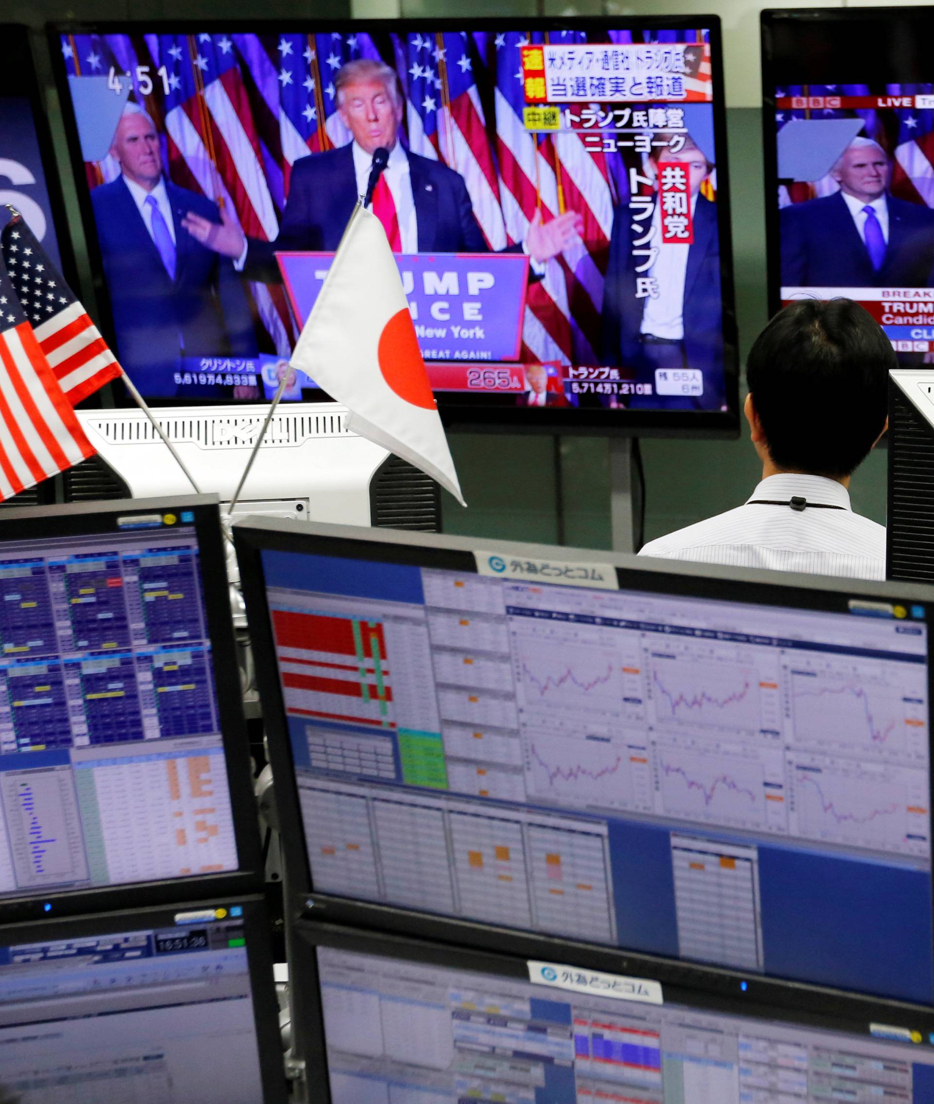 An employee of a foreign exchange trading company looks at monitors showing U.S. President elect Trump speaking on TV news in Tokyo