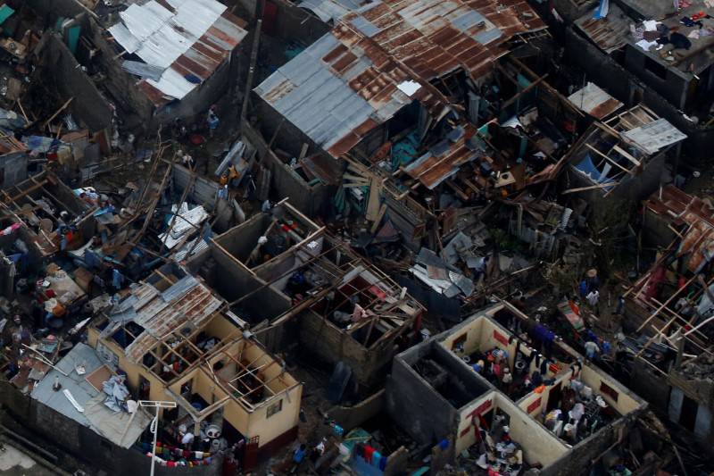 People walk next to destroyed houses after Hurricane Matthew passes Jeremie, Haiti