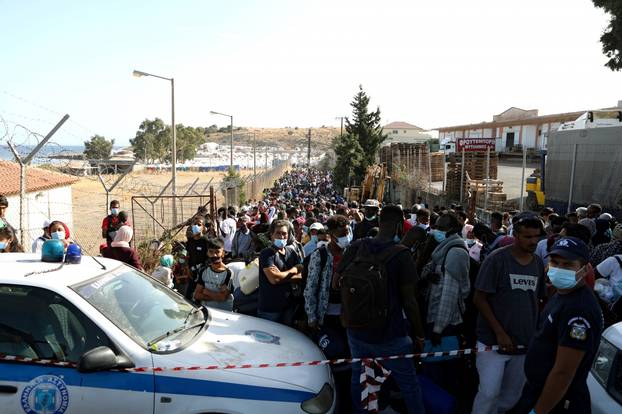 Refugees and migrants from the destroyed Moria camp wait to board busses to the port, from where they will be transferred to the mainland, on the island of Lesbos