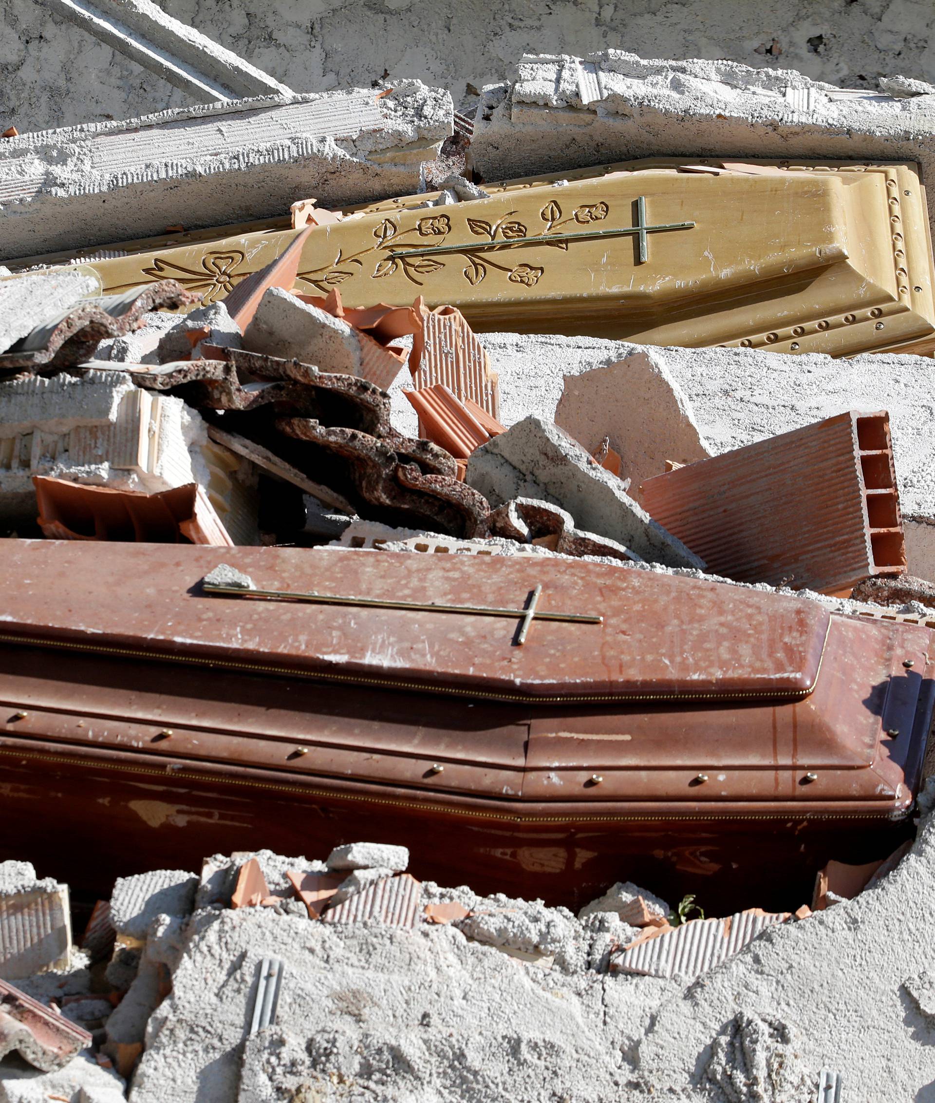 Coffins covered by debris are seen in a cemetery following an earthquake at Sant' Angelo near Amatrice