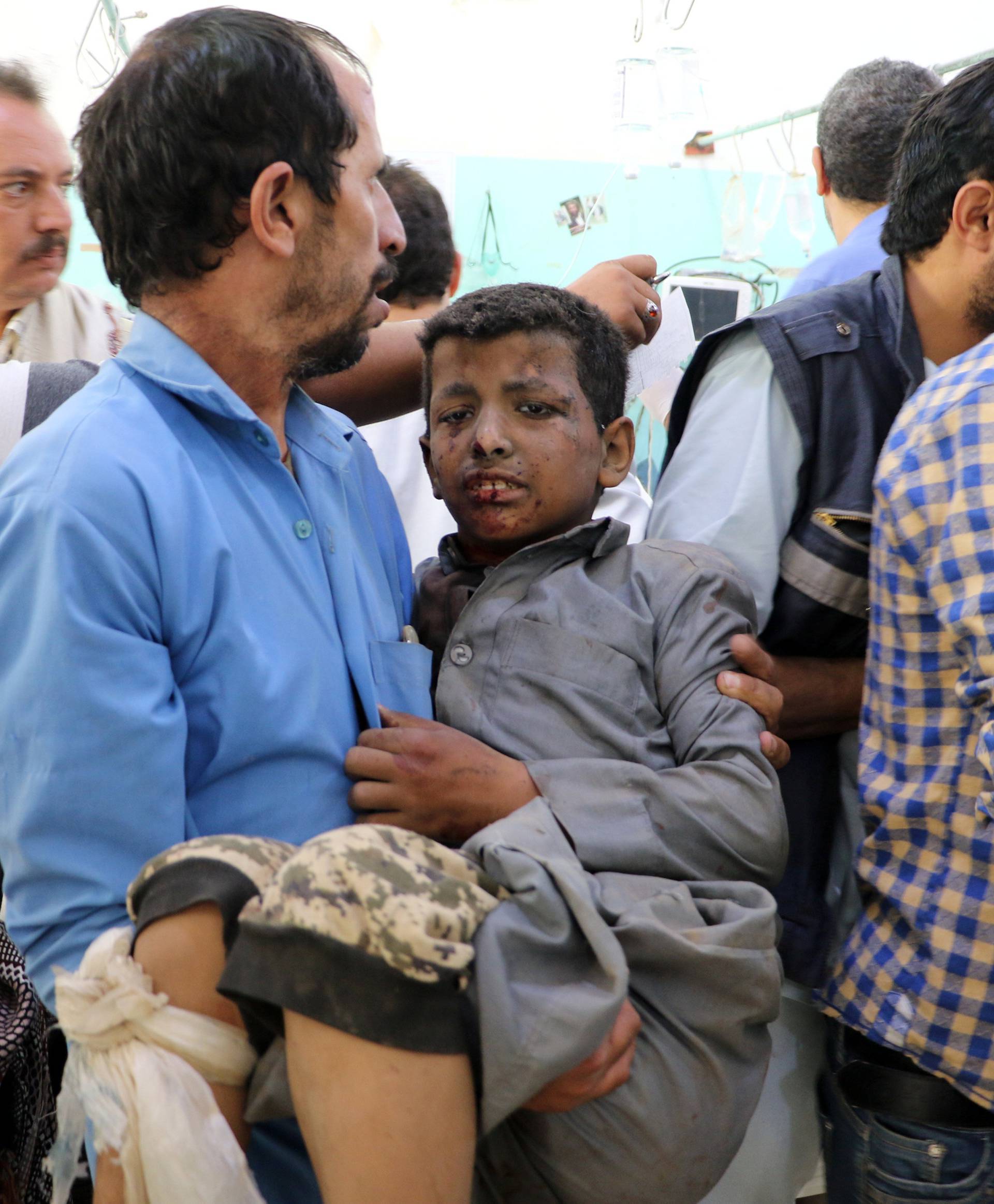 A Yemeni man holds a boy who was injured by an airstrike in Saada