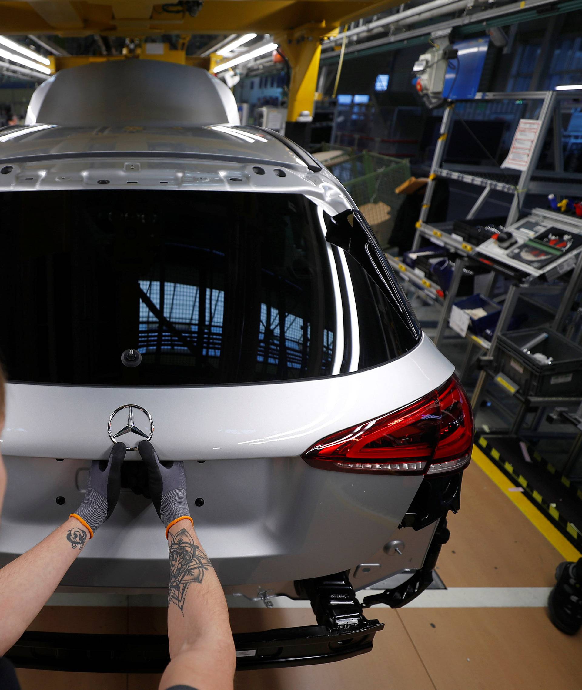 An employee of German car manufacturer Mercedes Benz installs the characteristic "Mercedes star" at a A-class model at the production line at the Daimler factory in Rastatt