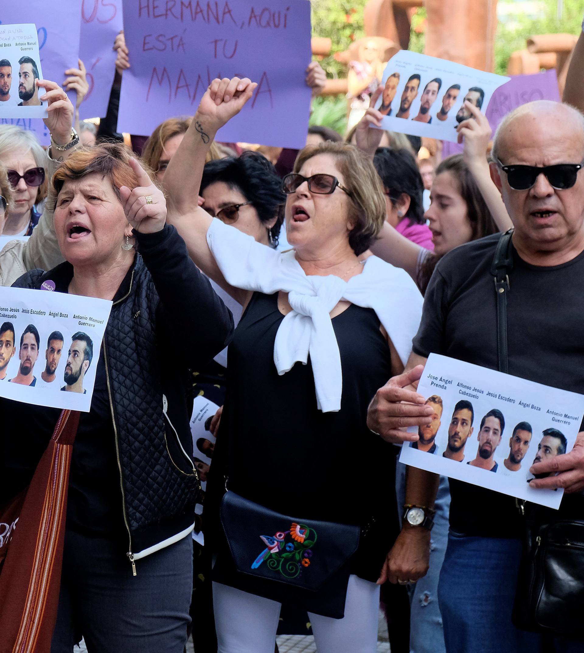 People shout slogans while holding signs during a protest outside the City of Justice in Valencia