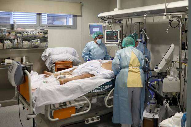 Medical workers take care of a patient infected with COVID-19 at the intensive care unit (ICU) of the Infanta Sofia University hospital in Spain