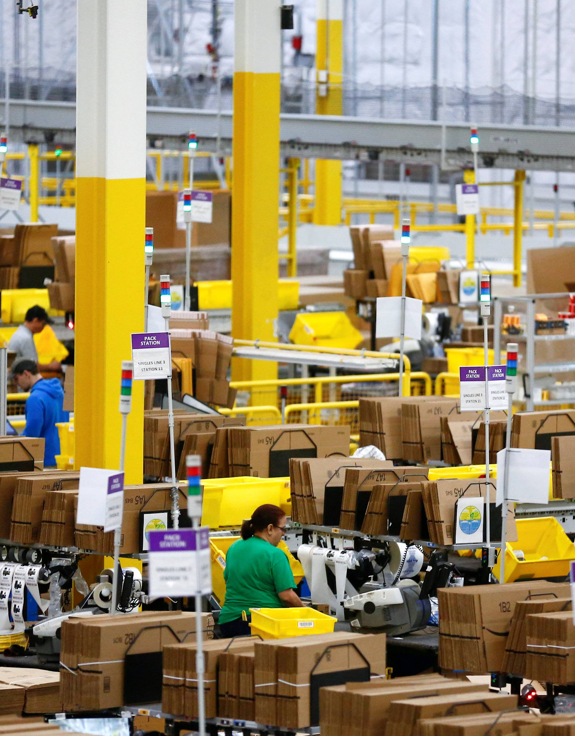 Employees work at pack stations at the Amazon fulfillment center in Kent