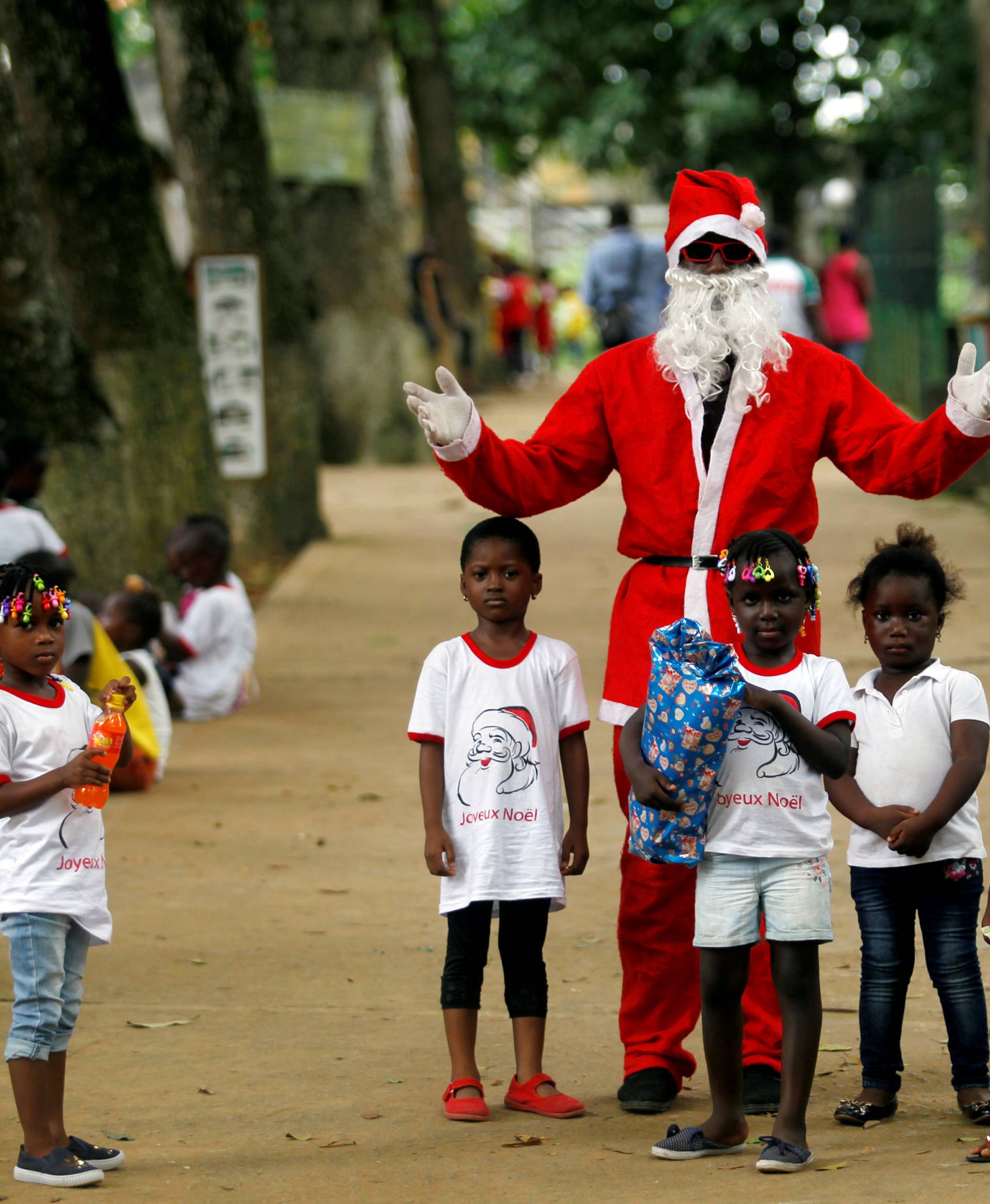 A man dressed as Santa Claus gestures as he poses with children during a visit at the zoo of Abidjan