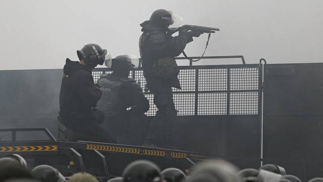 Kazakh law enforcement officers are seen on a barricade during a protest triggered by fuel price increase in Almaty
