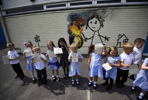 Reception class school children show off their drawings of a mural attributed to Banksy in Bristol