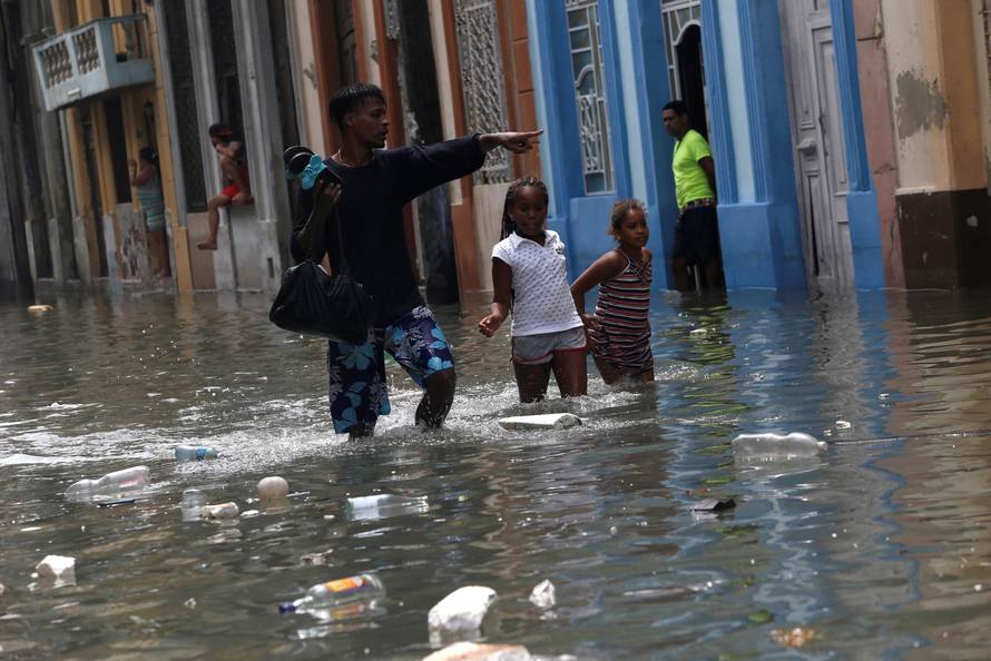 A man and two children wade through a flooded street,  after the passing of Hurricane Irma, in Havana
