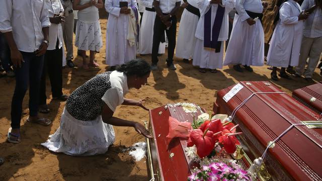 A woman reacts next to a coffin during a mass burial of victims at a cemetery near St. Sebastian Church in Negombo