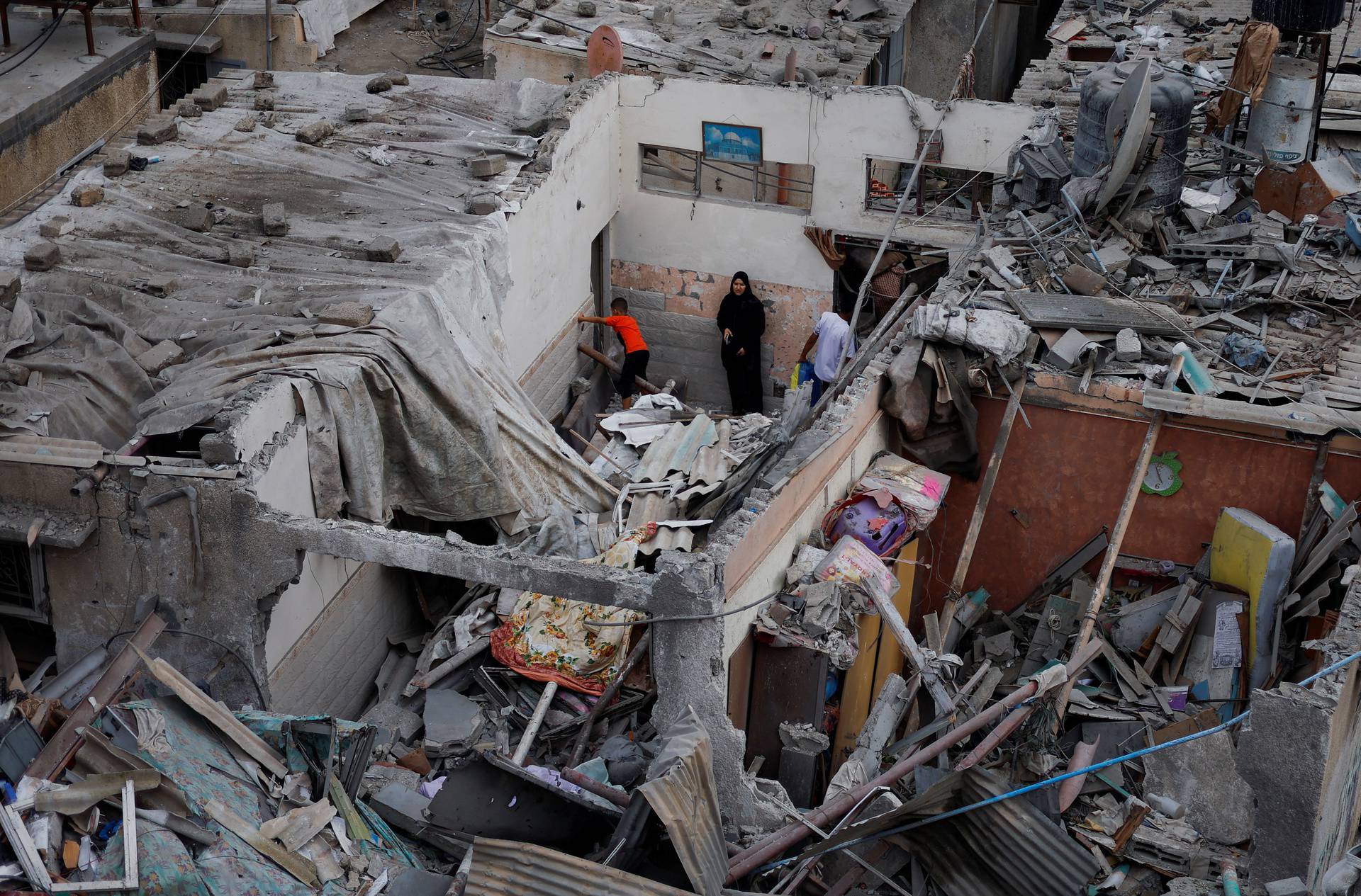 Palestinians check the damage at the site of Israeli strikes on houses in Khan Younis