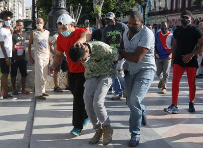 Plain clothes police detain a person during protests against and in support of the government, in Havana