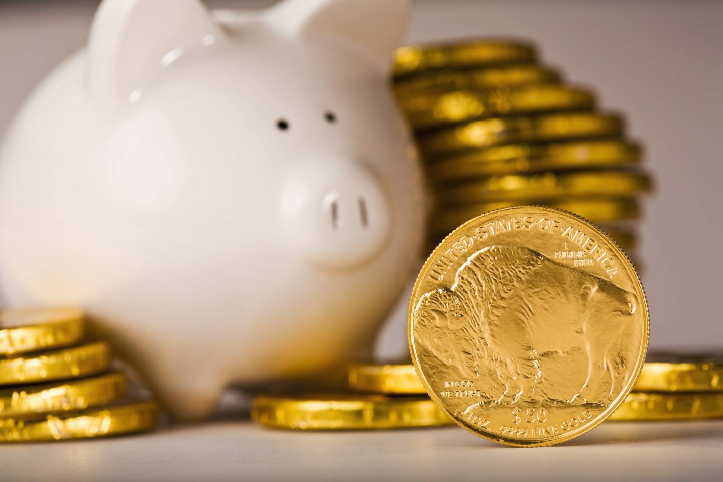 Gold coins savings piled around piggy bank