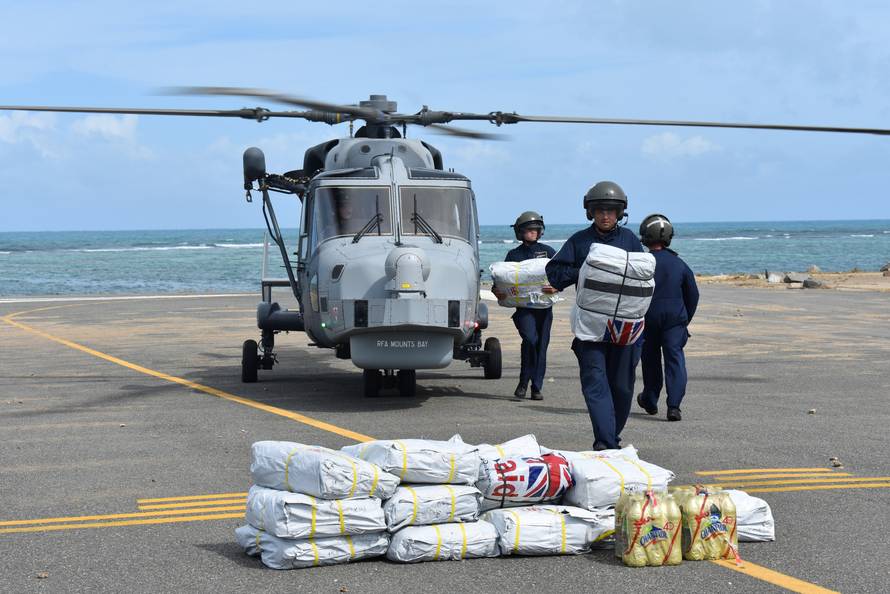 Royal Navy ground crew unload disaster supplies from a Wildcat helicopter at Tortola airport