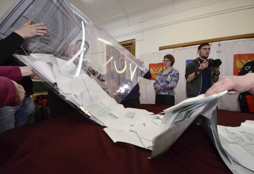 Members of a local election commission empty a ballot box before starting to count votes during the presidential election in Vladivostok