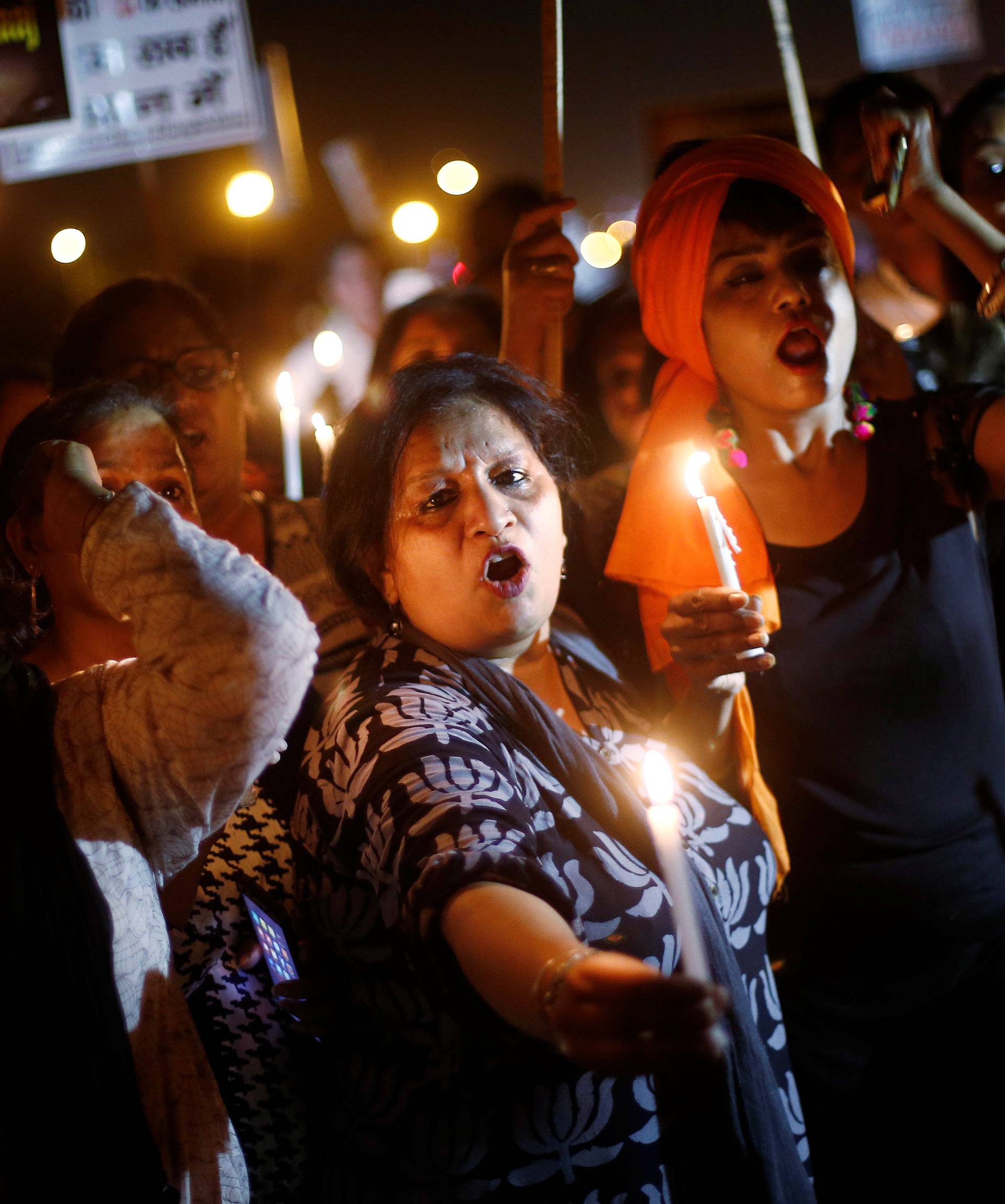 Women hold candles as they shout slogans during a protest against the rape of a ten-year-old girl, in the outskirts of Delhi