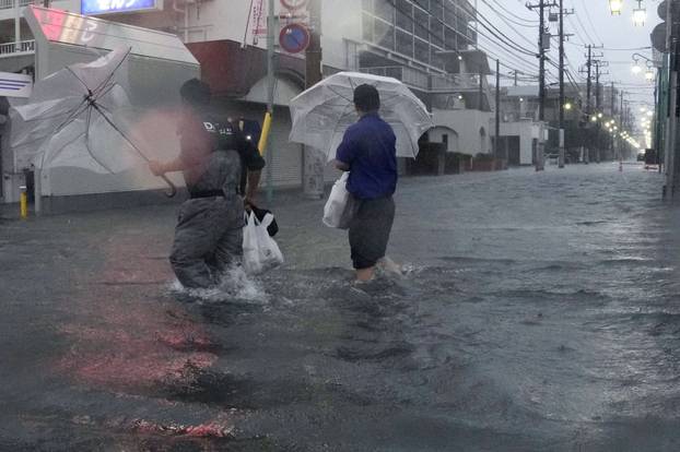 People wade through a flooded street as Typhoon Dujuan brings heavy rain, in Ichikawa