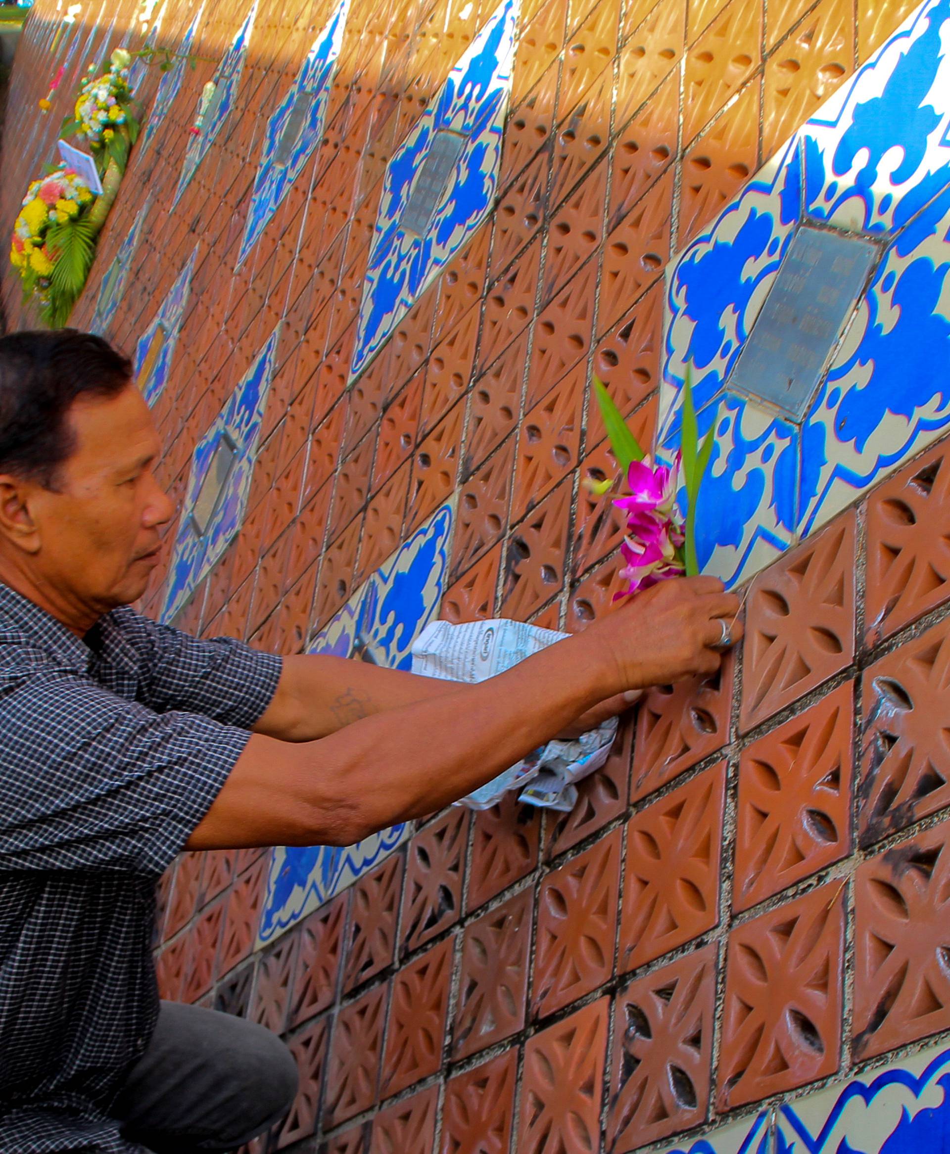 A man places flowers on a wave-shaped tsunami monument for victims of the 2004 tsunami in Ban Nam Khem, a southern fishing village destroyed by the wave, in Phang Nga Province