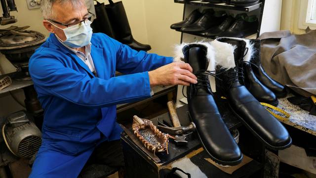 Romanian cobbler Grigore Lup presents a pair of oversized winter boots after finishing them