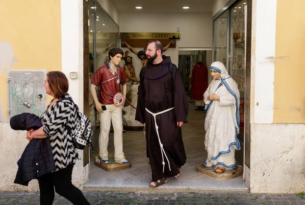 People walk past a figure depicting Carlo Acutis, in Rome