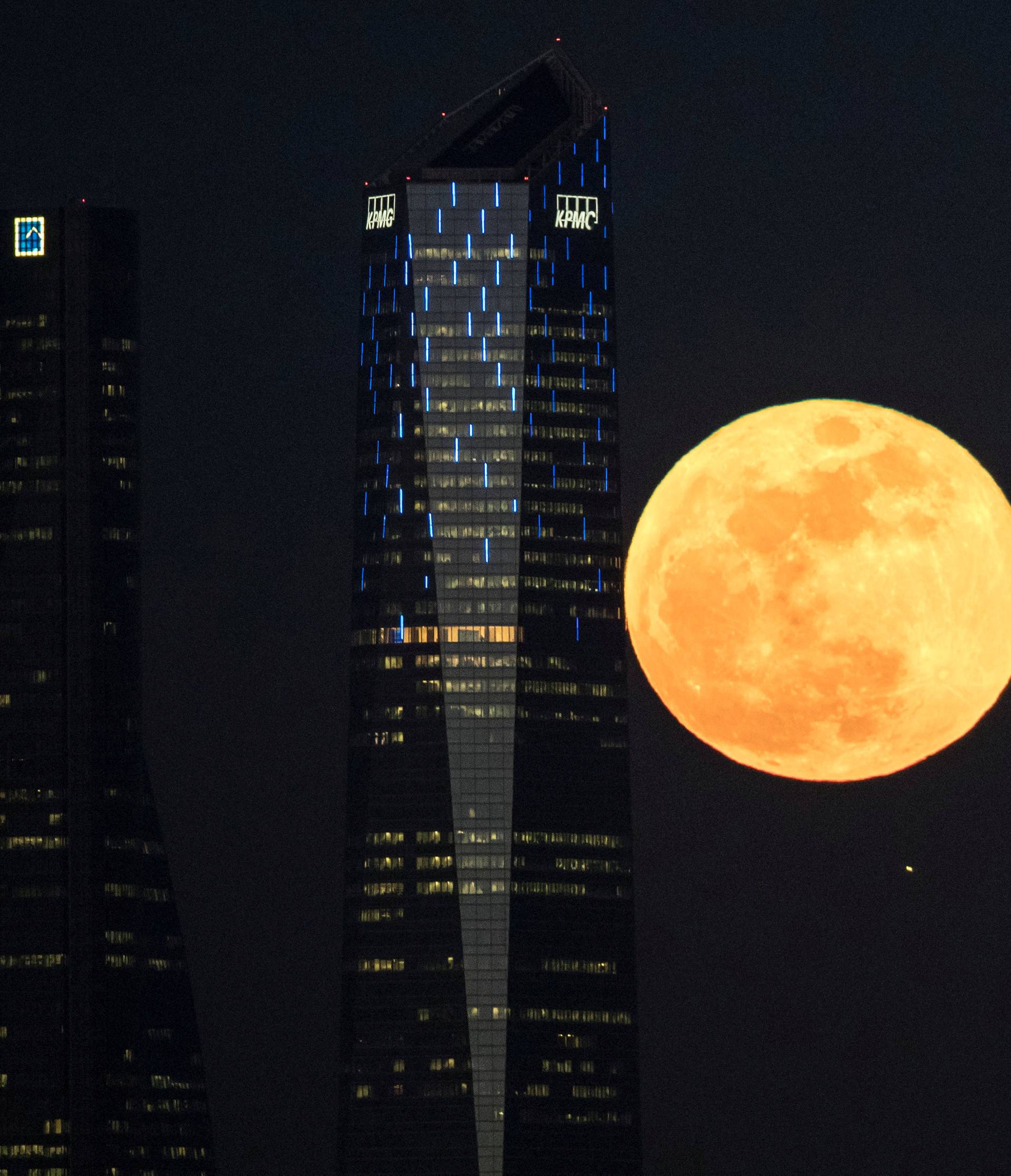 A full moon "supermoon" rises in between four towers in a skyscrapers area in Madrid
