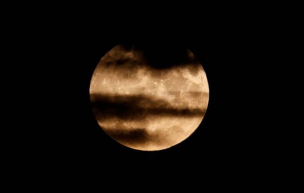 An aircraft flies over London and in front of the the super moon, know as the Blue Moon, in London