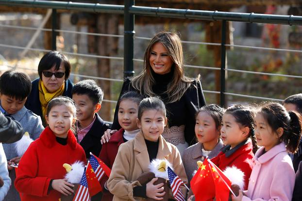 U.S. first lady Melania Trump smiles with children holding U.S. and China flags as she visits Beijing Zoo in Beijing,