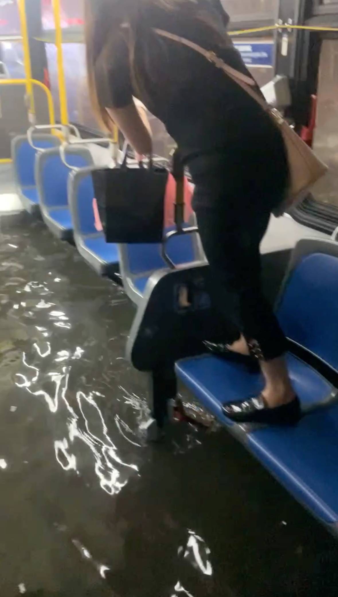 A passenger climbs on a bus seat while the bus drives through a flooded street, as remnants of Hurricane Ida brought torrential rains to the area, in New York City