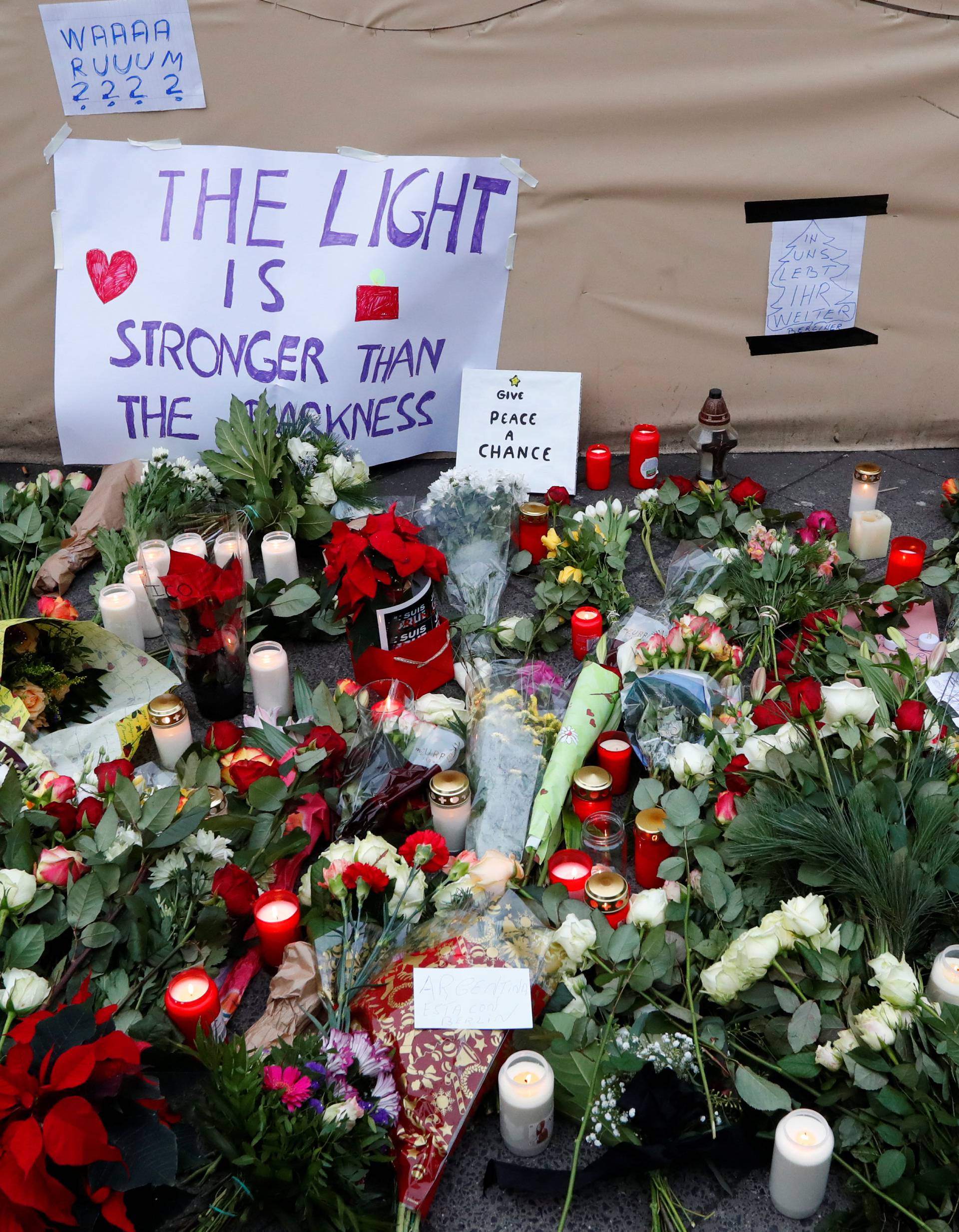 Flowers and posters are placed at the scene where a truck ploughed into a crowded Christmas market in the German capital last night in Berlin