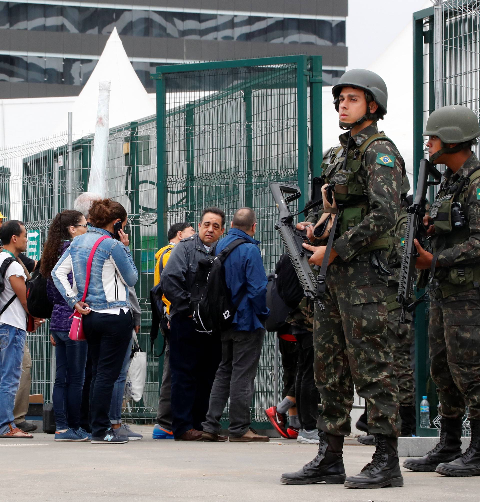 People queue at a security check to enter the main press center as Brazilian military police soldiers provide security at the 2016 Rio Olympics Park in Rio de Janeiro