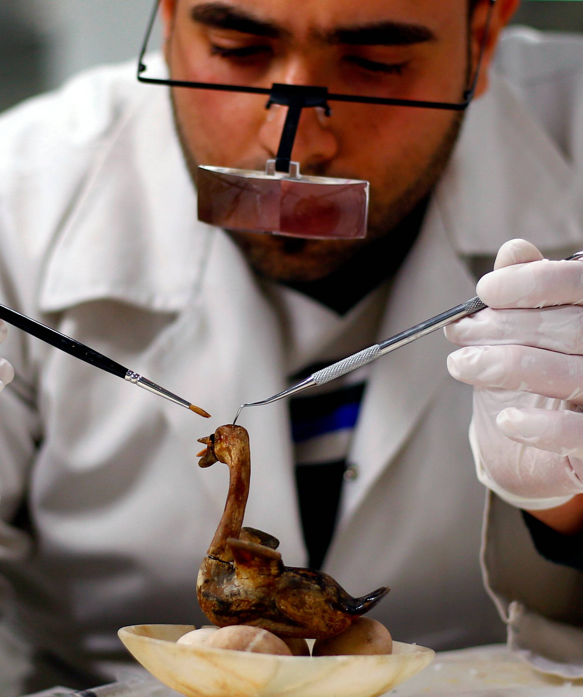 An Egyptian archaeological technician uses diagnostic instruments to renovate ancient toy 'A swan laying on eggs' which belonged to The Golden King Tutankhamun, in the conservation centre of the Grand Egyptian Museum, on the outskirts of Cairo