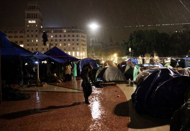 A person walks past a camp of tents at Plaza Catalunya square in Barcelona