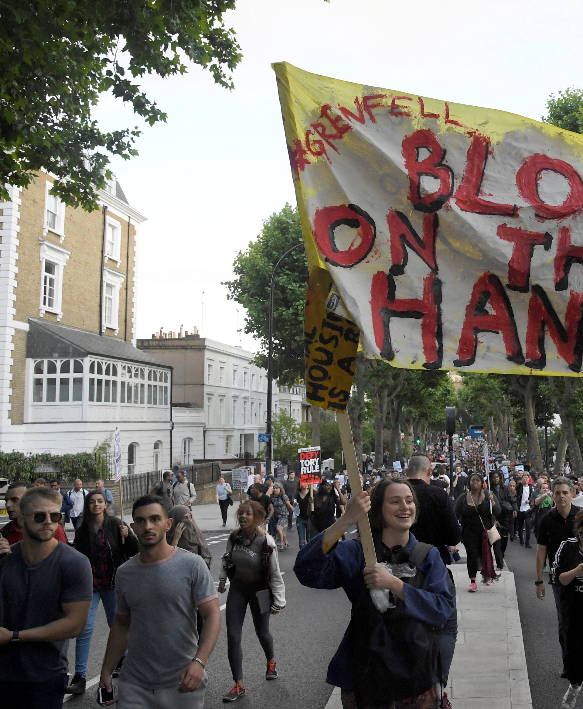 Demonstrators hold up banners during a march in Kensington, following the fire that destroyed The Grenfell Tower block, in north Kensington, West London