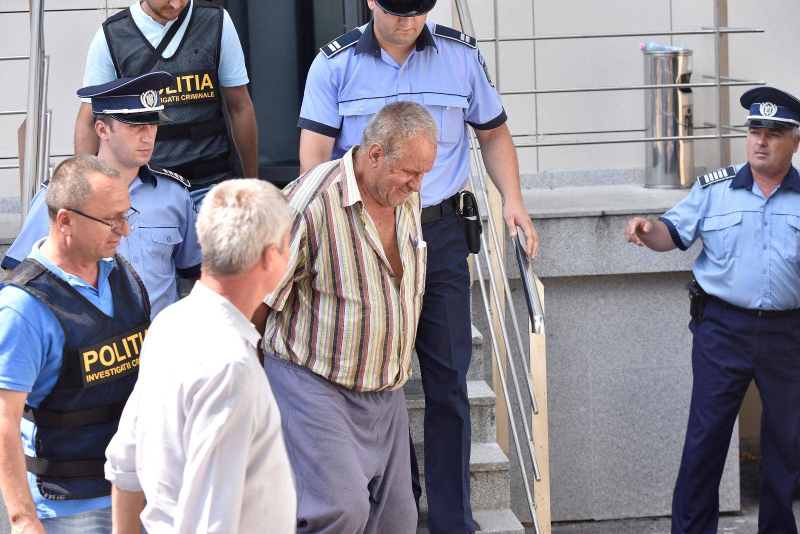 Gheorghe Dinca is escorted outside the court house in Craiova