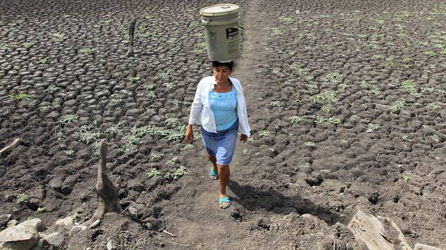 A woman carries a bucket of water on her head at Santa Isabel  town.