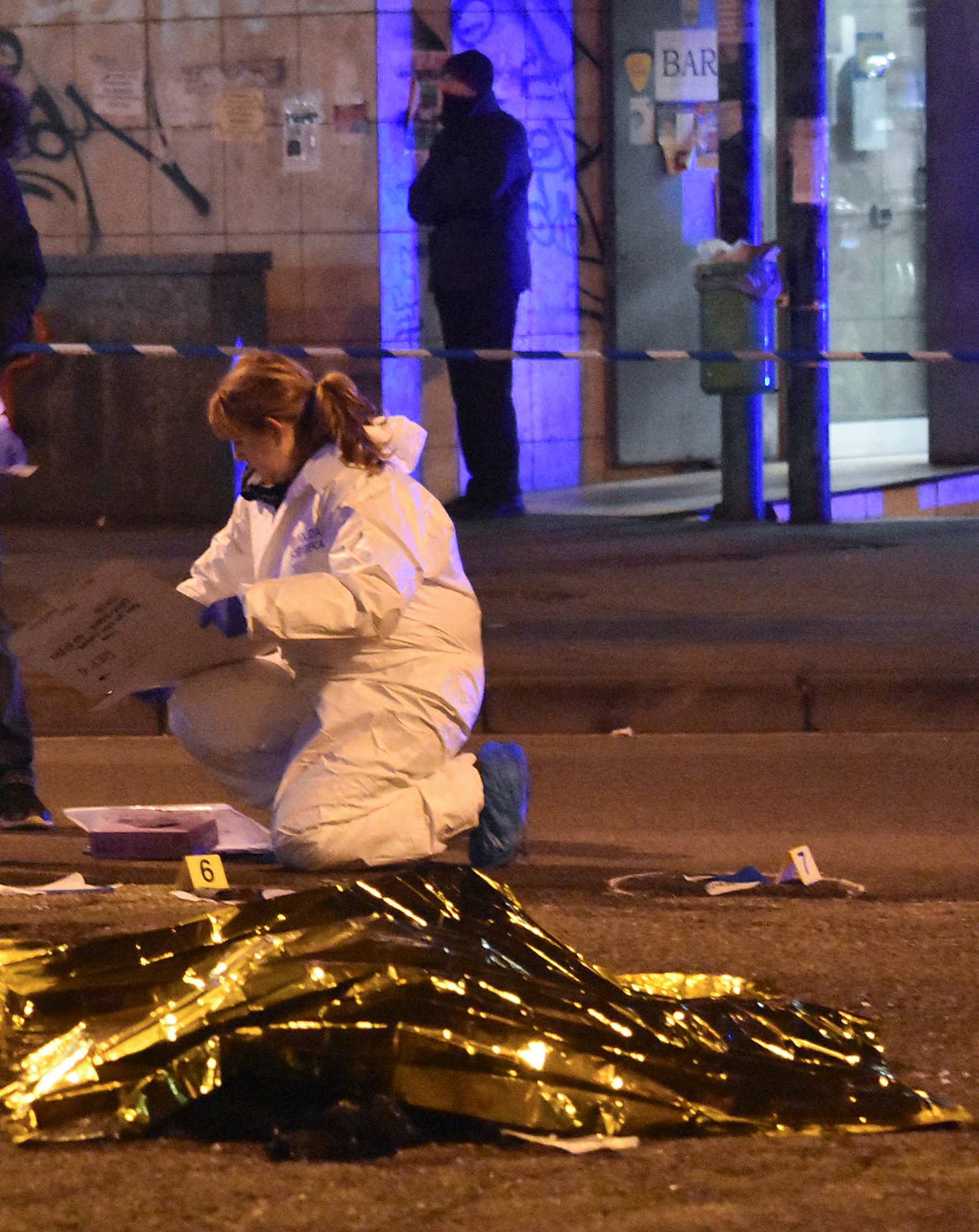 The body of Anis Amri, the suspect in the Berlin Christmas market truck attack, is seen covered with a thermal blanket next to Italian officers in a suburb of the northern Italian city of Milan