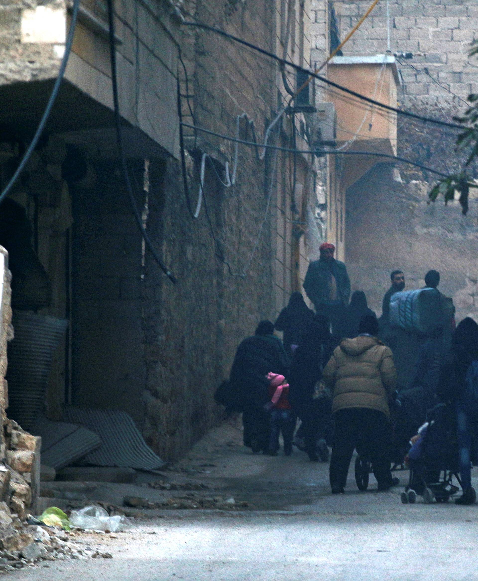 People carry belongings as they flee deeper into the remaining rebel-held areas of Aleppo