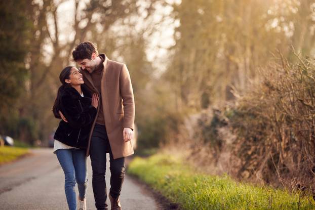 Loving Young Couple Walking Through Winter Countryside Together