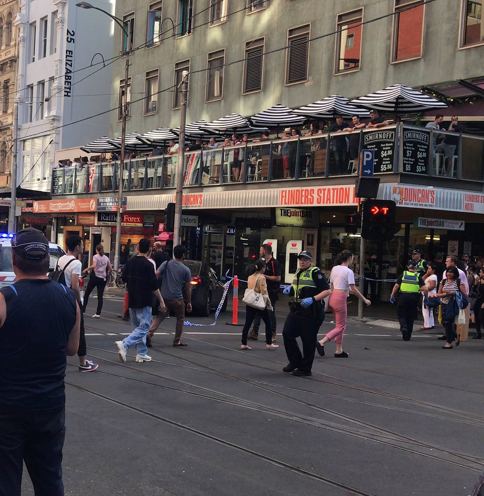 Police and emergency services attend the scene of an incident involving a vehicle on Flinders Street, as seen from Swanson Street