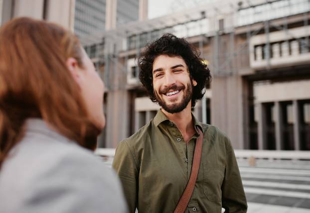 Portrait of successful and laughing business man in conversation with female partner on city street