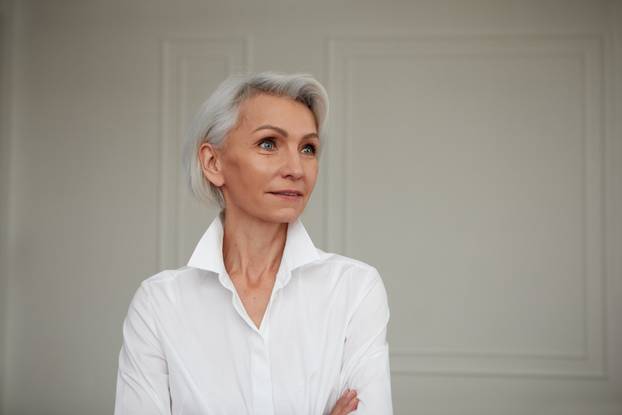 Close up portrait of beautiful older woman standing by wall