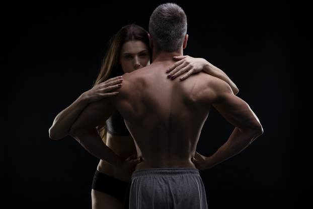 Young adult muscular man and woman. Sexy couple on black background
